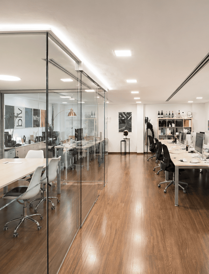 Oficina moderna y luminosa con estaciones de trabajo, sala de reuniones y zona de descanso, diseñada para fomentar la colaboración y la creatividad en un entorno profesional.